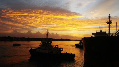 Silhouette of ship at harbor during sunset