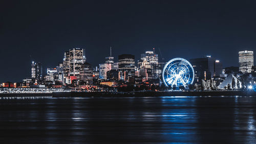 Illuminated city buildings by river at night