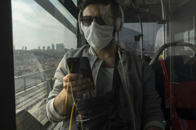 Man using mobile phone in train seen through window