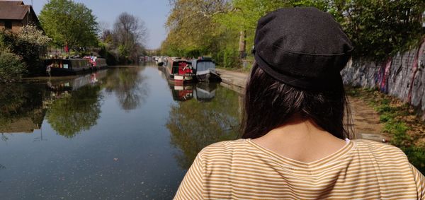Rear view of woman standing by canal