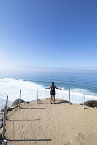 A lady with backpack looks at the ocean during a hike in san diego