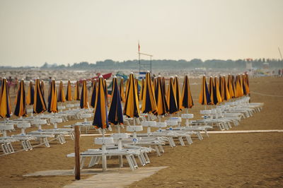 Deck chairs on beach against sky