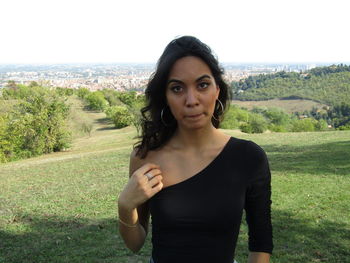 Portrait of beautiful young woman standing on field