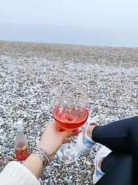 Midsection of woman holding drink at beach