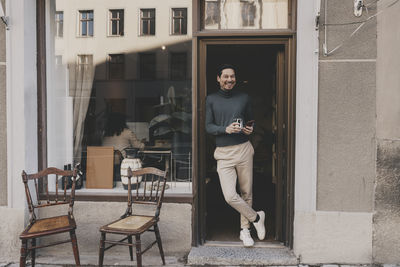 Smiling male entrepreneur leaning on office doorway