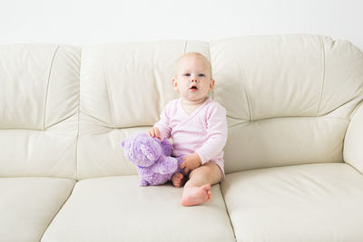 Cute baby girl sitting with toy at home