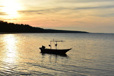 Silhouette sailboat in sea against sky during sunset