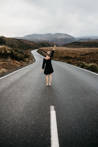 Woman standing on road against sky