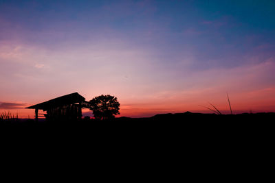 Silhouette houses against sky during sunset