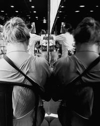 Rear view of man and woman standing on mirror