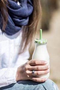 Midsection of young woman holding milk bottle