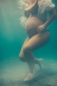 Low section of young woman swimming underwater