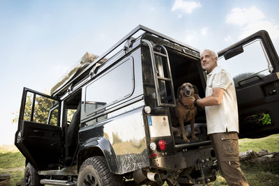 Senior man with dog at cross country vehicle