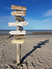 Information sign on beach against sky