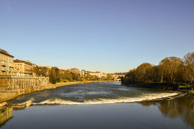 River amidst buildings against clear blue sky