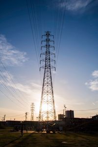 Low angle view of electricity pylon on field against sky