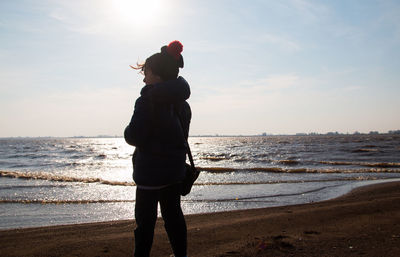 Child loking at the sea wearing winter clothes