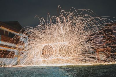 Wire wool spinning on field against sky at night