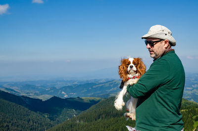 Man with dog on mountain against sky