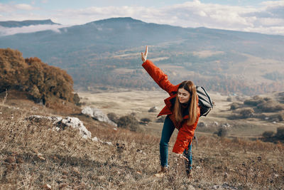 Full length of young woman standing on mountain