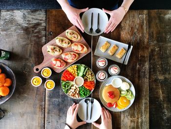 Cropped image of friends having food on wooden table