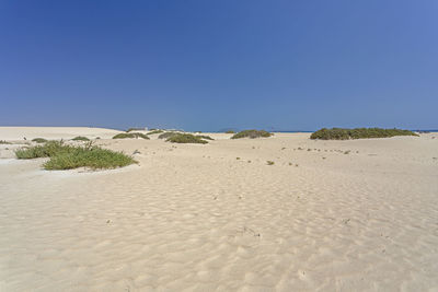 Scenic view of desert against clear blue sky