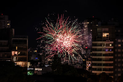 Firework display by buildings in city at night