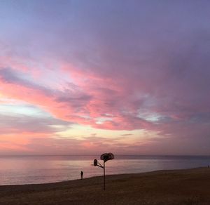 Silhouette beach against sky during sunset