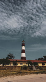 Lighthouse by building against sky