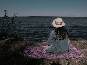 Rear view of woman looking at sea shore against clear sky