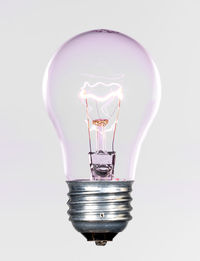 Close-up of illuminated light bulb against white background