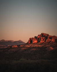 Rock formations on landscape against sky during sunset