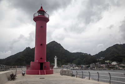 Lighthouse on pier against cloudy sky