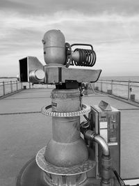 Close-up of coin-operated binoculars by sea against sky