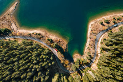 Aerial view of winding road by lake and forest