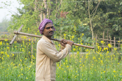 Farmer holding spade on his shoulder at farm land