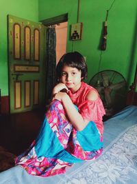 Portrait of cute girl sitting on bed at home