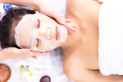 Cropped hands applying face mask to woman at beauty spa