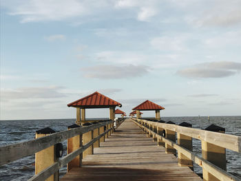 Wooden pier on sea against sky