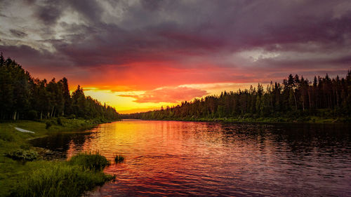 Scenic view of lake against dramatic sky during sunset