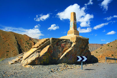 Rocks built structure against cloudy sky