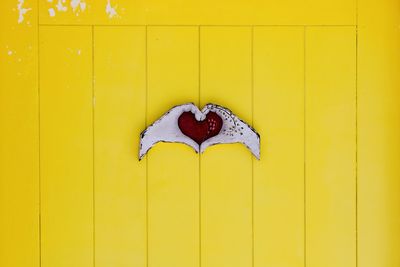 Close-up of red heart shape on yellow wall