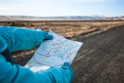 Close-up of hands holding map on road