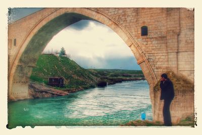 Man standing by bridge against sky