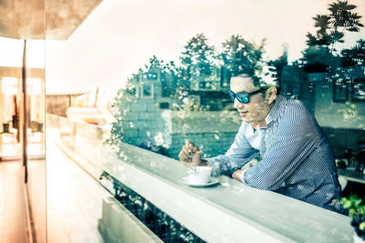 Reflection of man having coffee in restaurant on glass