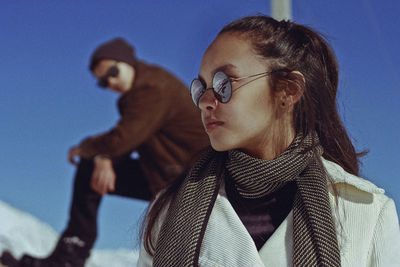 Low angle view of young woman in sunglasses against clear sky