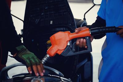 Midsection of man refueling motor scooter at gas station