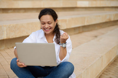 Young woman using laptop while sitting on steps