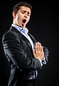 Opera singer singing while standing against black background