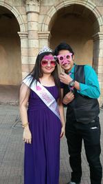 Portrait of bride with male friend holding prop while standing outdoors